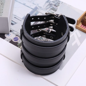 Macro detail of black punk leather wristband with triple straps and metal buckles