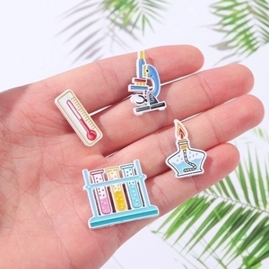 Creative science enamel pin set featuring microscope, beaker, and alcohol lamp icons