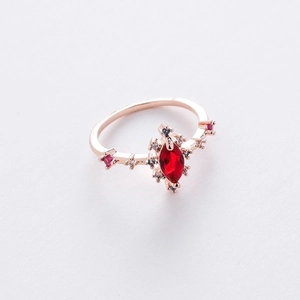 Detailed macro view of rose gold ring with marquise cut ruby and zircon accents