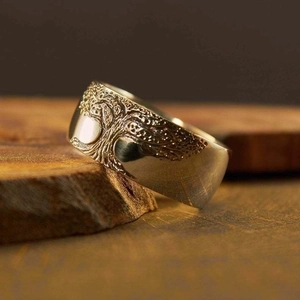 Silver vintage tree of life ring with embossed pattern on a rustic wooden texture