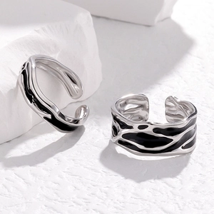 Adjustable stainless steel couple rings with black enamel inlay on stone background