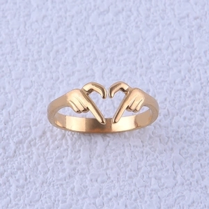 Minimalist golden heart gesture ring made of stainless steel on a textured background