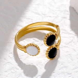 Adjustable gold stainless steel ring with black and white enamel circles on textured background