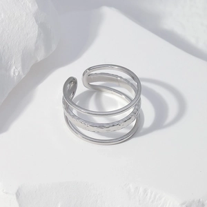 Detail of silver triple-layered open ring with hammered texture on white stone base