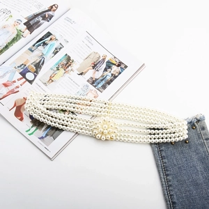Detail of four-row pearl waist chain with elegant flower buckle over denim fabric
