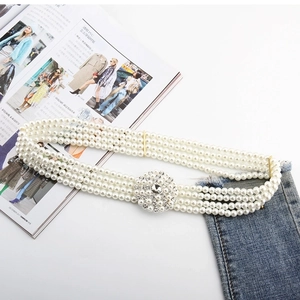 Detail of three-layer pearl waist belt with a sparkling rhinestone floral buckle