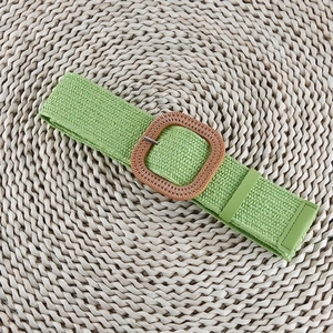 Detail of green woven elastic belt with square straw texture buckle on a round mat