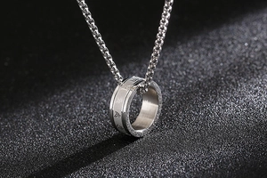 Makroaufnahme des silbernen Mantra-Ring-Anhängers an einer Box-Kette mit Reliefgravur