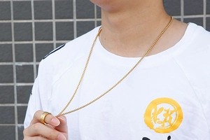 Nahaufnahme von goldenem Drehring und Halskette mit sechs-Wort-Mantra an einem Modell