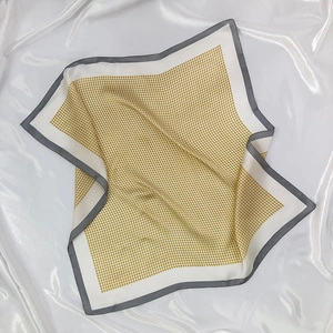 Detailed view of yellow houndstooth silk-like scarf with soft texture and grey edges