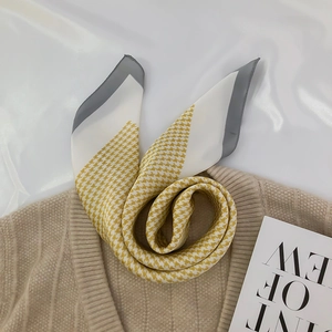 Close-up of yellow and grey houndstooth silk scarf on a beige sweater with magazine detail