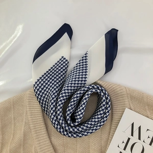 Blue and white houndstooth silk scarf elegantly styled on a beige knit sweater