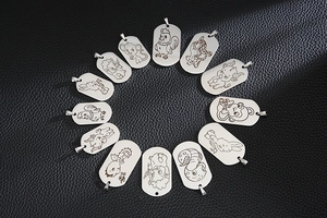 Detail of twelve stainless steel zodiac pendants on a black leather background