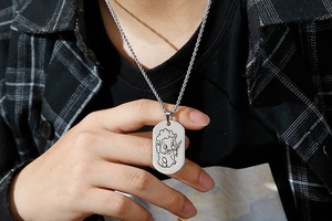 Macro shot of a silver rectangle pendant with sheep engraving on a twisted rope chain