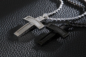 Macro shot of silver and black cross pendants with brushed texture on black leather