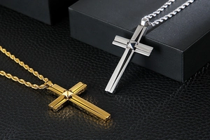Close-up of gold and silver double-layered cross pendants on twist chains with gift box