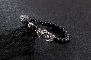 Detail of beaded bracelet with silver Pi Xiu charms and a Fu character bead on dark stone