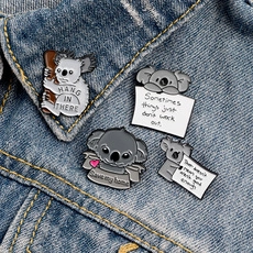 Detail view of cute koala enamel pins on denim jacket featuring motivational quotes