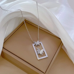 Macro view of butterfly pendant on silver stainless steel chain over silk fabric