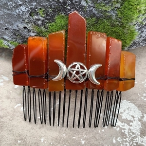 Detail of natural orange crystal hair comb with silver crescent moon and star on mossy rock