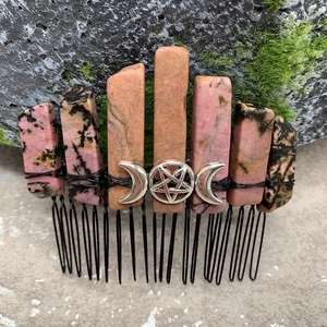 Detailed view of handmade pink crystal hair comb with silver crescent moon on moss rock