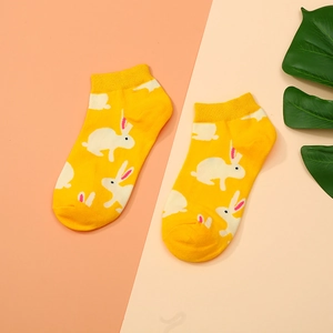 Close-up of yellow cotton ankle socks featuring white rabbit patterns with a soft texture