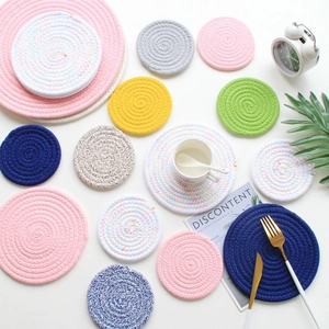 Flat lay of colorful braided cotton rope coasters in various sizes on a white table