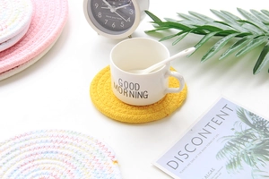 Detail of hand-woven round cotton heat-resistant coaster in vibrant yellow and pink