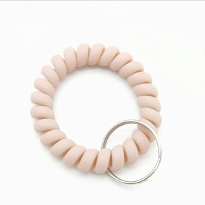 Close-up of a matte pink spiral wrist keychain with a silver metal ring accessory