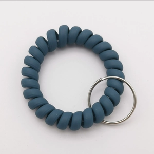 Detail of a matte grey-blue spiral telephone wire wristband with a silver metal key ring