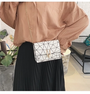 Detailed view of white crossbody bag with geometric pattern and golden chain strap