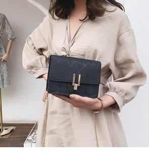 Detail of black geometric crossbody bag featuring gold chain strap and metal clasp lock