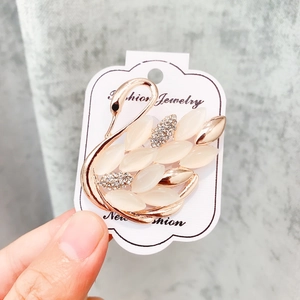 Vue détaillée d'une broche cygne en or rose avec pierres opalescentes et petits cristaux