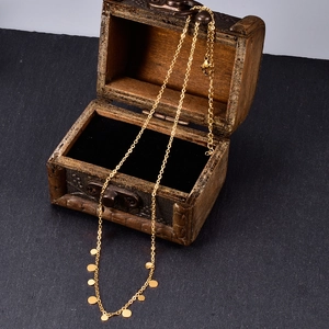 Detail of gold necklace with circular pendants on vintage wooden chest background