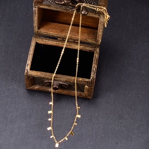 Detail of gold necklace with rectangular metal tags draped from a wooden gift box