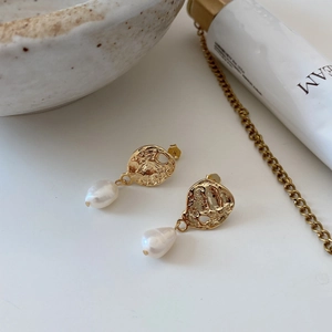 Close-up of gold baroque pearl earrings with hammered metal texture and vintage design