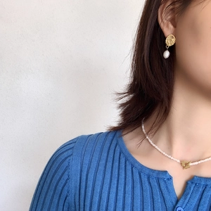 Close-up of Baroque pearl earrings with hammered gold disks and matching necklace on model