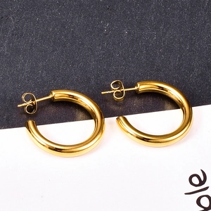 Close-up of gold-plated C-shaped hoop earrings with a high-polished mirror finish