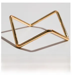 Macro shot of minimalist gold metal stand with geometric folded structure and shiny finish
