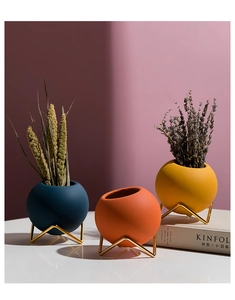 Modern spherical ceramic vases in blue, orange, and yellow with gold metal stands