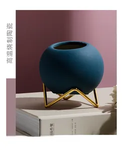 Detailed view of dark blue matte ceramic sphere vase with an elegant gold metal tripod base