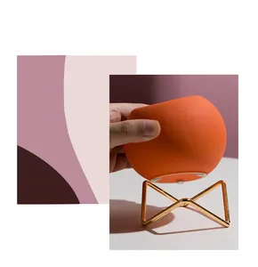 Detail of matte orange ceramic vase with minimalist golden geometric metal stand