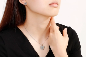 Detail view of silver heart pendant necklace and earrings set with crown and M engraving