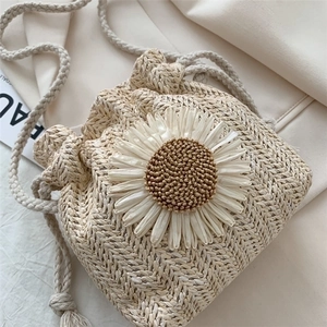 Handmade straw bucket bag with large white daisy decoration and drawstring closure