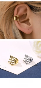 Detailed view of punk style skull hand ear cuffs in gold and silver metal finish