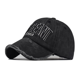Close-up of 3D embroidery and distressed frayed edges on a washed black cotton baseball cap