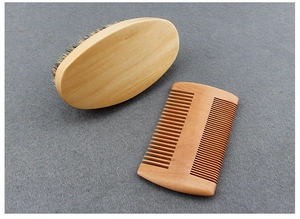 Detailed view of boar bristle beard brush and double-sided wooden comb on gray felt