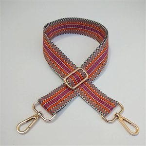 Detail of adjustable embroidered bag strap with colorful stripes and gold metal hooks