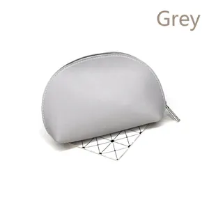 Close-up of a gray shell-shaped makeup bag with silver zipper and matte faux leather