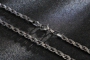 Detail of twisted curb chain link and secure lobster clasp on black leather background